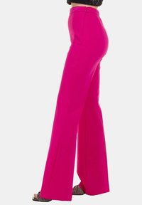 Pantaloni a gamba larga fucsia a vita alta realizzati in tessuto morbido, dotati di chiusura con cerniera sul retro e senza motivi o decorazioni visibili.