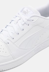 Lähikuva valkoisesta Puma-tennarista, jossa on teksturoitu nahkapinta, ja näkyvissä nauhat, logo sekä yksityiskohdat sivulla ja pohjassa.