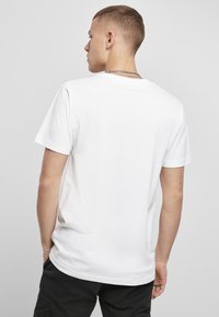 Hvid t-shirt med korte ærmer lavet af bomuld. Har en rund halsudskæring og en afslappet pasform. Minimalistisk design, ingen synlige mønstre eller accenter.