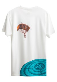 T-shirt bianca in cotone con un design grafico di una figura che fa parapendio e un motivo circolare blu nella parte inferiore. Maniche corte e colletto rotondo.
