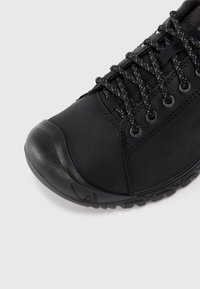 Czarne buty trekkingowe z teksturowaną cholewką, wzmocnionym czubkiem oraz wzorzystymi sznurowadłami. Posiadają solidną podeszwę dla przyczepności i stabilności.