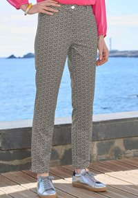 Geprinte broek in zwart en crème met een geometrisch patroon, met een slim fit en een zijzak. Gepaard met zilveren sneakers.