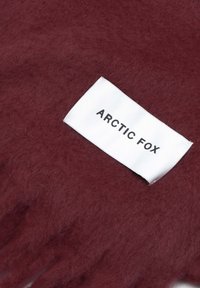 Burgunderfarbene Wollhandschuhe mit weicher Textur und einem weißen Label, auf dem "ARCTIC FOX" in Schwarz steht. Der Stoff scheint dick und warm zu sein.