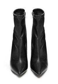 Pár černých kožených kotníkových bot s špičatými špičkami a postranními zipy, pohled zepředu na bílém pozadí.
