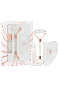 Zestaw do pielęgnacji twarzy z kamieniami szlachetnymi, który zawiera wałek, gua sha i serum; materiały obejmują akcenty w kolorze różowego złota, przezroczysty kryształ oraz kształt serca.