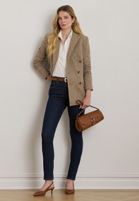 Dvojniki z gumbom rjav blazer s houndstooth vzorcem, bela srajca z gumbi, temno tesne jeans hlače, rjav pas, rjava torba in rjave salonarje z zaostrenim nosom.