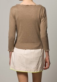 Brązowy dziergany sweter z rękawami do połowy przedramienia, ze ściągaczem na dole. Do tego biała spódnica z obwódką w neonowo zielonym kolorze.