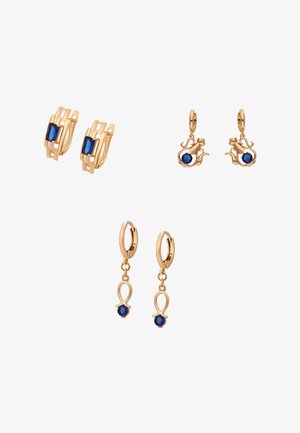 Tre par guldbelagte øreringe med blå ædelstene, med geometriske, dyre- og abstrakte løbedesigns, arrangeret på en hvid baggrund.