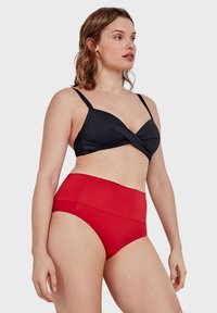 Crni bikini gornji deo sa uvijenim prednjim dizajnom; crveni bikini donji deo visokog struka. Glatka, rastezljiva tkanina, podesive naramenice.