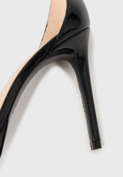 Chaussure à talons aiguilles en cuir verni noir avec un bout pointu et un talon stiletto fin sur un fond clair.