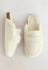 Pantofole in pelliccia sintetica bianca con design imbottito, dotate di cinturino regolabile e suola testurizzata per aderenza e comfort.