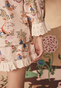 Sukienka w kwiatowy wzór z miękkiej różowej tkaniny, zdobiona misternymi wzorami, warstwowym krojem oraz szczegółowym wykończeniem z koronki ażurowej.