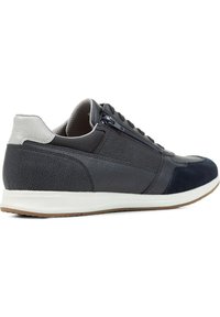 Zapatillas deportivas para hombre que combinan cuero gris oscuro y gamuza azul marino, con una superficie texturizada, detalles en gris, suela blanca y cremallera lateral.