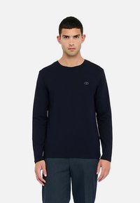 Mørkeblå langærmet t-shirt i bomuldsblanding med rund halsudskæring og diskret logodetalje på brystet, kombineret med bukser i stribet stof.