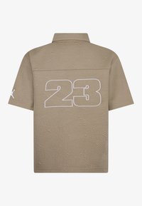 Šviesiai rudos trumpomis rankovėmis polo marškiniai su geometrine tekstūra, ant nugaros turi baltą "23" spaudą ir subtilų logotipo akcentą ant rankovės.