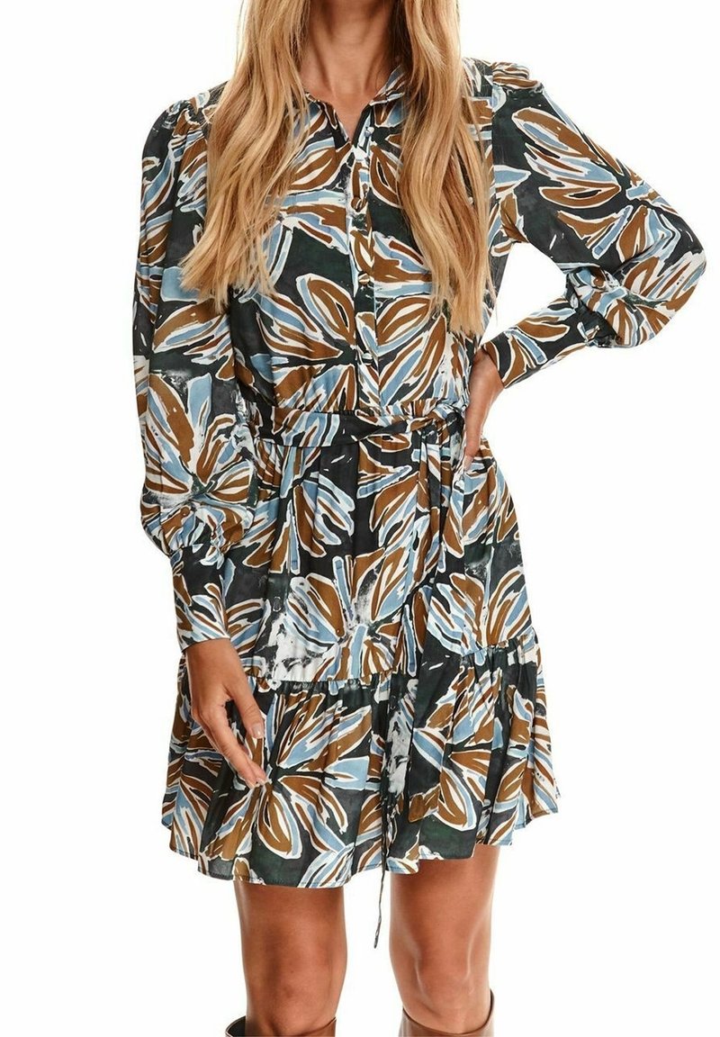 Blommig klänning med mörk bakgrund och blå samt bruna lövmönster, långärmad, knäppning framtill och kjol med volanger och dragsko.