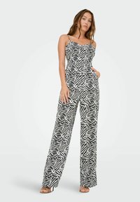 Jumpsuit con patrón en blanco y negro, con un corsé ajustado, piernas anchas y tirantes finos. Presenta un diseño abstracto similar a hojas y una textura suave.