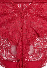 Lencería de encaje rojo que presenta intrincados patrones florales, un diseño con escote en V y una banda sólida roja. Texturizada con delicados detalles.