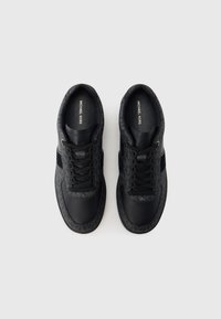 Black sneakers featuring a textured fabric and smooth leather upper, with a lace-up design and logo accents on the sides and tongue.