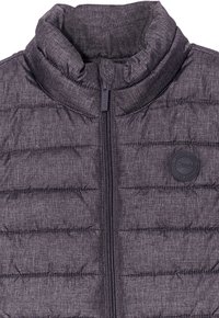 Gilet in piuma grigia con alto colletto, texture trapuntata, zip frontale e una toppa rotonda con logo sul lato sinistro.