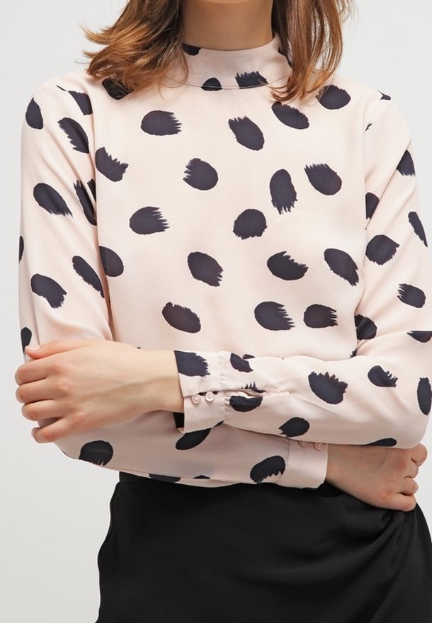 Blusa a maniche lunghe in tessuto rosa chiaro con motivi a pennellate nere, colletto alto e polsini con bottoni, dal tocco setoso.