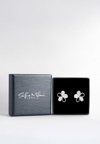 Silverfärgade blommiga örhängen prydda med klara stenar, presenterade i en svart texturerad låda med en mjuk innerfoder.