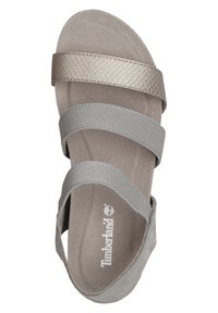 Szare sandały z trzema elastycznymi paskami; jeden z nich ma metaliczny wzór w wężową skórę. Miękka zamszowa wkładka i logo Timberland na podeszwie.