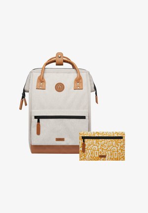 Beige fabric backpack with brown leather accents, featuring a front zip pocket, top handle, and an accompanying yellow patterned pouch.