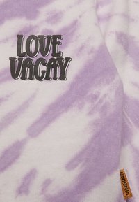Sweatshirt roxa com padrão tie-dye e texto "LOVE VAGAY" em fonte preta bold. Tecido suave com um acabamento texturizado; apresenta uma pequena etiqueta laranja na lateral.