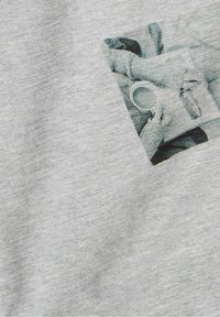 T-shirt in cotone grigio con una grafica testurizzata di mani che tengono una tazza, con colori smorzati e una stampa rettangolare sul davanti.