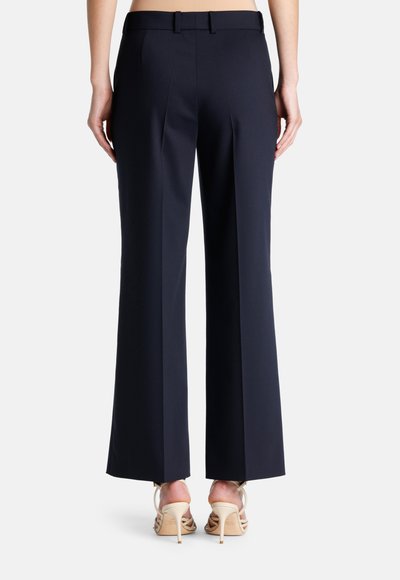 Navyblauwe wijde broek met een getailleerde pasvorm, met een gladde textuur, twee achterzakken en een riem. Draagt men met beige hoge hakken.