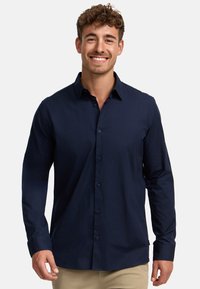 Camisa de botones de manga larga en color azul marino, con cuello y pliegue frontal. Textura suave, diseño ajustado y puños abotonados.