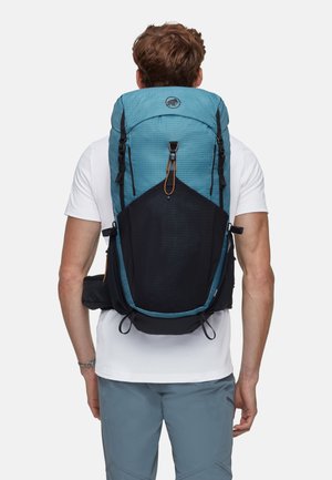 Rucksack aus teal- und schwarzem Stoff mit Karomuster, Klappe mit Verschluss oben, Kordelzug, seitlichen Riemen und gepolstertem Rückenstütze.