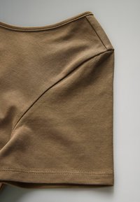 Braune Baumwollstoffshorts mit glatter Textur, geschwungenen Nahtdetails und umgeschlagenem Bund. Das Design zeichnet sich durch einen schlichten, figurschmeichelnden Schnitt aus.