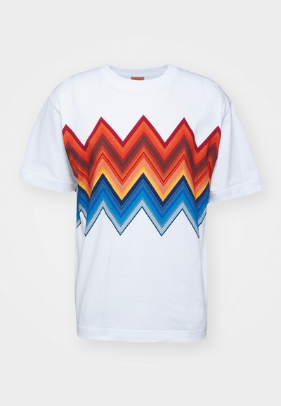 Balta medvilnės marškinėliai su daugiakrtiniu zigzagų raštu raudonos, oranžinės, mėlynos ir juodos spalvų ant priekinės dalies. Trumpomis rankovėmis ir apykakle.