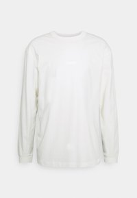 Vit långärmad t-shirt i bomull, med rund halsringning och en subtil logopatch i en ljusare nyans på framsidan.