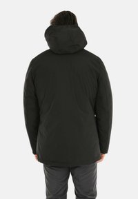 Giacca nera, isolata, con cappuccio, caratterizzata da un'esterno liscio e tattile e una vestibilità comoda. Presenta un design semplice e minimalista.