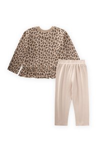 Ilgtērpu tops ar leoparddrukas rakstu zeltainā krāsā un volānu apakšu, kopā ar ribotām zeltaini bēšām legingām ar elastīgu jostu.