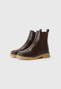 Botas de cuero marrón hasta el tobillo con paneles laterales elásticos, punta redondeada y una suela de goma marrón texturizada. Adecuadas para uso casual.