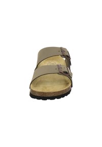 Brown leather two-strap sandal with adjustable metal buckles, cork footbed, and rubber outsole. Flat design offers casual comfort and support.