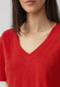 Rode V-hals t-shirt van zacht materiaal, met een ontspannen pasvorm en korte mouwen, voorzien van een gestructureerde afwerking en nette stiksels.