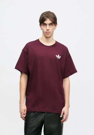 Burgundy színű, oversized pamut póló kerek nyakkal és rövid ujjakkal, a mellrészen egy kis fehér Adidas trefoil logóval.