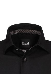 Schwarzes Hemd mit Knopfleiste und strukturiertem Kragen, mit einem gemusterten Innenfutter. Der Stoff ist glatt mit einer gewebten Textur. Logoschild sichtbar.