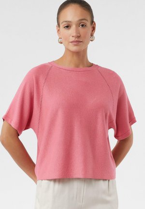 Różowy t-shirt z krótkim rękawem, okrągłym dekoltem i fakturowanym materiałem. Posiada raglanowe rękawy oraz subtelne detale wzdłuż szwów.