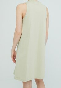 Ärmlös klänning i ljusgrön, tillverkad av ett mjukt tyg. Har en enkel, avslappnad passform med rund halsringning och når ovanför knäet.