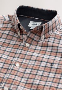 Chemise à carreaux dans des nuances d'orange, de bleu et de blanc ; dotée d'un col boutonné, de boutons blancs et d'un logo brodé sur la poitrine.