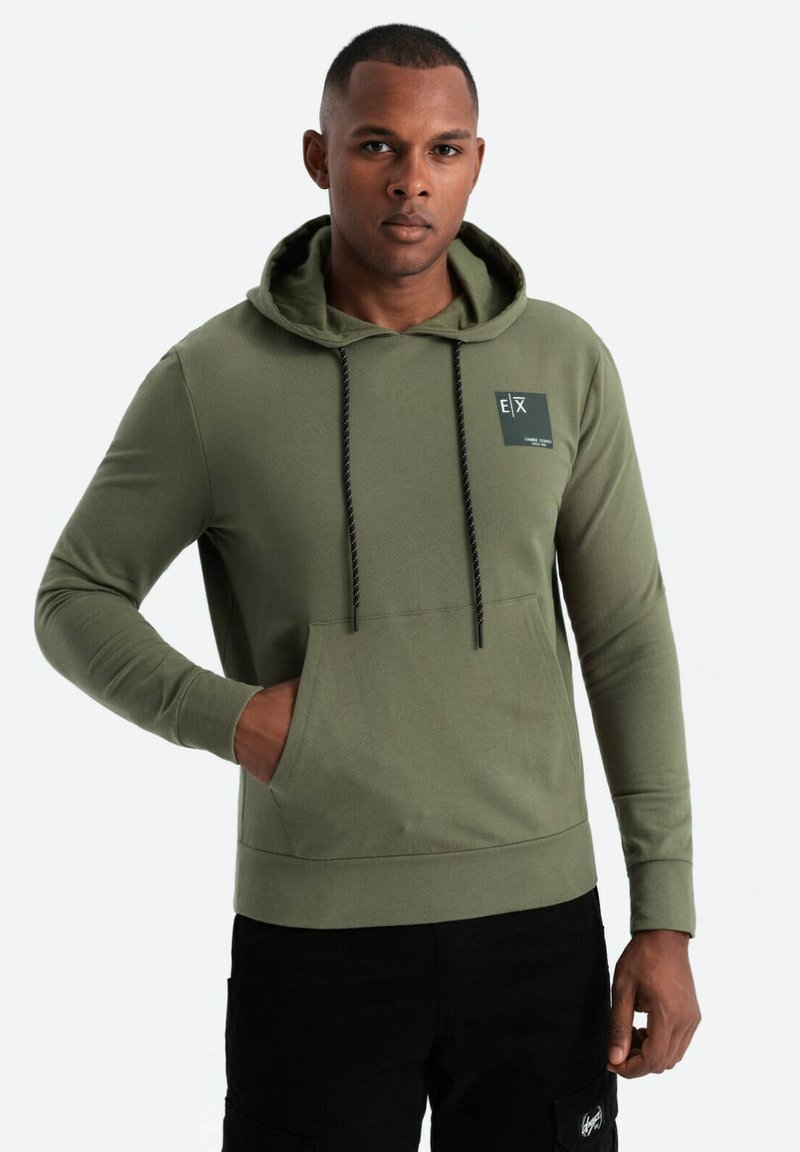 Felpa color verde oliva con tasca a marsupio, coulisse regolabile, dettagli neri e una piccola etichetta con il logo sul petto. Tessuto misto cotone.
