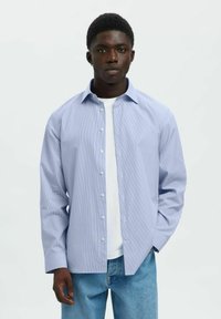 Lichtblauw gestreept shirt met een knoopsluiting, lange mouwen en een comfortabele pasvorm, gedragen over een wit T-shirt.