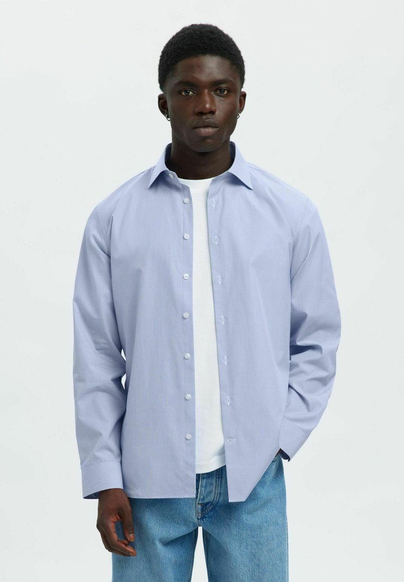 Lichtblauw gestreept shirt met een knoopsluiting, lange mouwen en een comfortabele pasvorm, gedragen over een wit T-shirt.