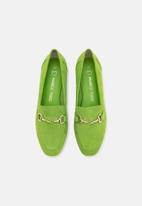 Mocasines de ante verde con suela plana, con un detalle de cadena en tono dorado en la parte frontal y una plantilla acolchada para mayor comodidad. Talla 37.
